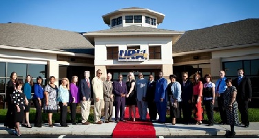 Board and Staff standing in front of new building at Lowes Dr.